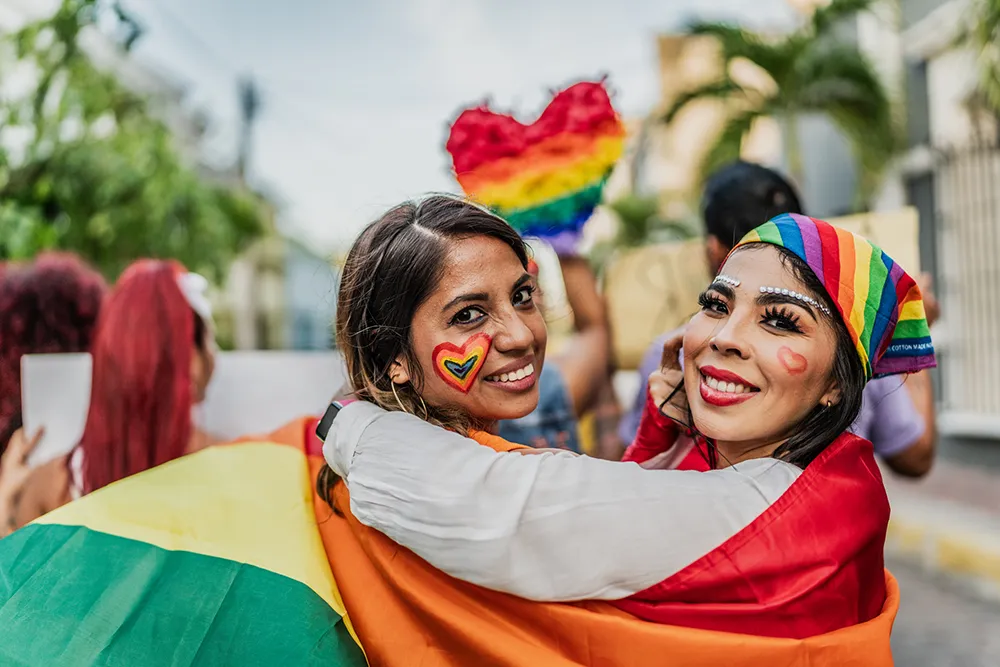 Colourful female couple with facepainting and rainbow pride flag