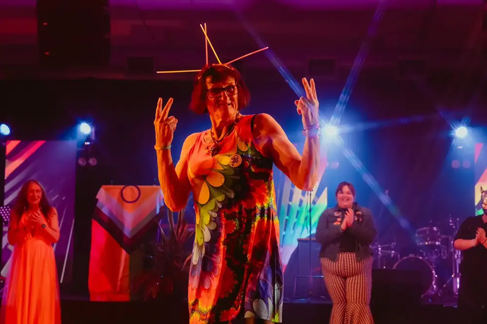 Sarah on stage holding her hands up in the air and smiling